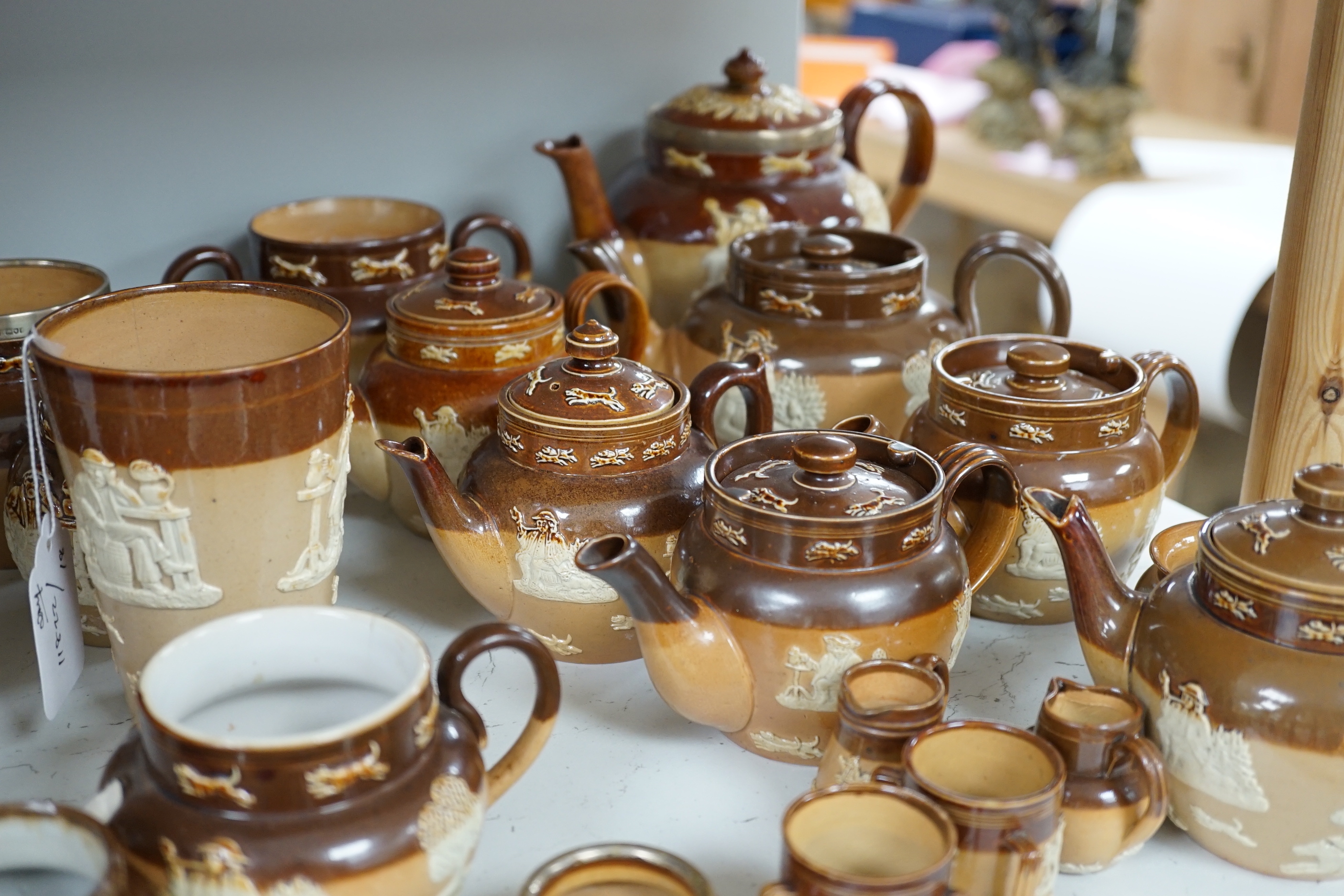 An assortment of Doulton stoneware including teapots, miniature tygs and twin handled pots, some silver mounted, largest 22cm wide